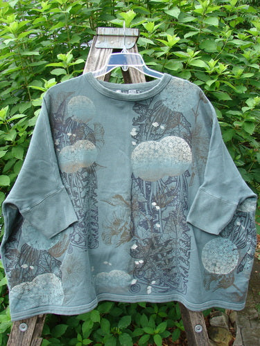 Barclay Fleece Banded Sleeve Colors Sweatshirt Moon Flower Olive Drab OSFA displayed on a swing, showcasing its generous boxy shape, dolman sleeves, and distinct moon flower pattern.