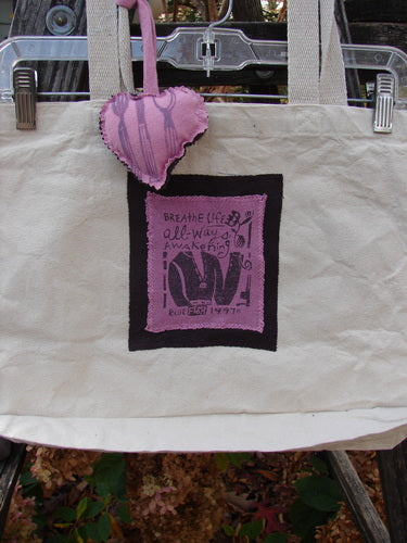 1995 PMU Patched Tote Bag Sling Vintage Logo Frayed Natural Pink One Size on a metal rack, featuring colorful puffy heart accents and a signature patch, highlighting its sustainable, vintage design from Bluefishfinder.com.