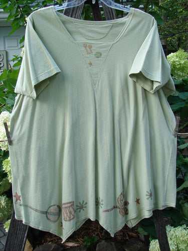 1994 Leaf Top Music Garden Aloe Size 2: A classic green shirt featuring a unique painted hemline, triangular neckline, and garden-themed design, epitomizing Blue Fish's vintage charm and creative expression.