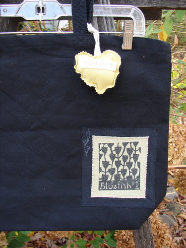 1995 PMU Patched Tote Bag Sling featuring a heart-shaped tag and frayed patches, showcasing Bluefishfinder.com's vintage style with extra-long straps and a gusseted bottom.