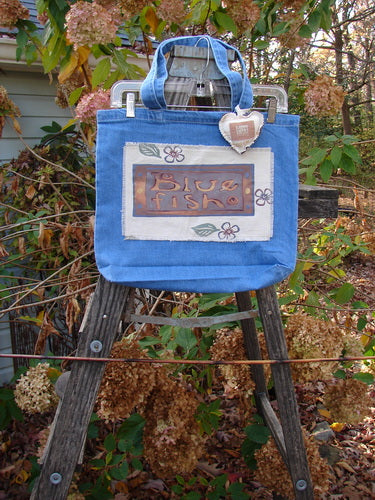 2001 PMU Patched Tote Bag Summer Frayed Logo Washed Denim One Size, displayed on a wooden ladder, featuring tote-length shoulder straps, a generous top opening, and a colorful puffy heart accent.