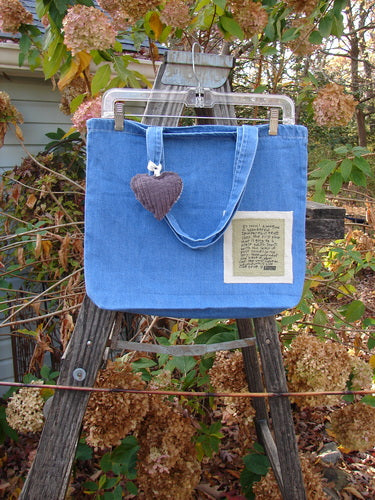 2001 PMU Patched Tote Bag Summer Frayed Logo Washed Denim One Size with a colorful puffy heart accent, displayed on a wooden ladder, showcasing its generous top opening and tote-length shoulder straps.