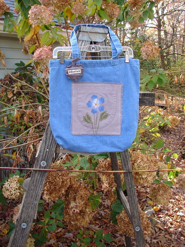 2000 PMU Patched Cotton Pocket Tote Bag Frayed Daisy Washed Denim One Size displayed on a wooden ladder, showcasing its signature Blue Fish patch, daisy patch, and puffy heart accent charm.