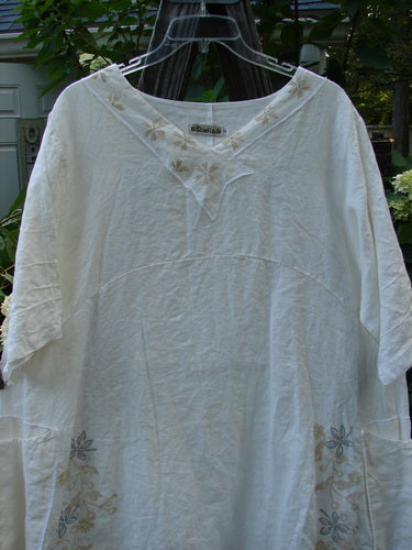 Barclay Linen Cross Over Urchin Tunic Dress Daisy Cloud Size 2 displayed on a hanger, showcasing its V-neckline, drop shoulders, and double drop flop side pockets.