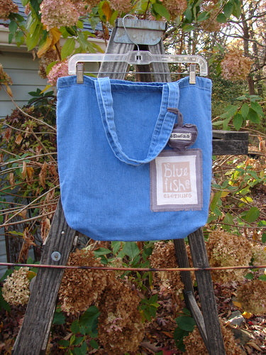 2000 PMU Patched Cotton Pocket Tote Bag Frayed Daisy Washed Denim One Size displayed on a wooden ladder, featuring tote-length shoulder straps, a puffy heart charm, and decorative daisy patches.