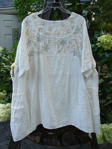 Barclay Linen Cross Over Urchin Tunic Dress Daisy Cloud Size 2 hanging on a clothesline, showcasing its V neckline, drop shoulders, and floral pattern.