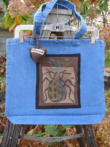 1996 PMU Patched Tote Bag Beetle Washed Denim One Size, featuring a spring beetle and signature patch, with tote-length shoulder straps and a generous top opening, showcasing Bluefishfinder.com's vintage style.