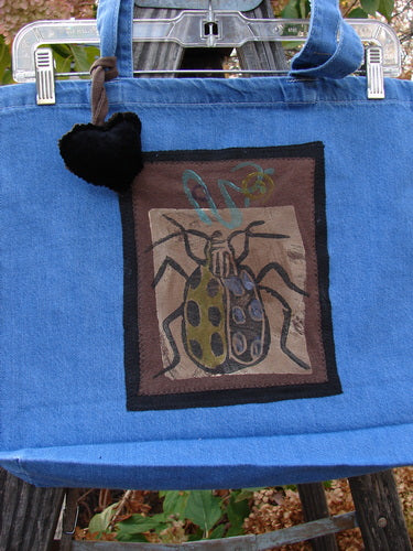 1996 PMU Patched Tote Bag Beetle Washed Denim One Size, featuring a beetle patch, puffy heart accent, tote-length shoulder straps, and generous opening, highlighting Bluefishfinder.com's commitment to sustainable vintage designs.