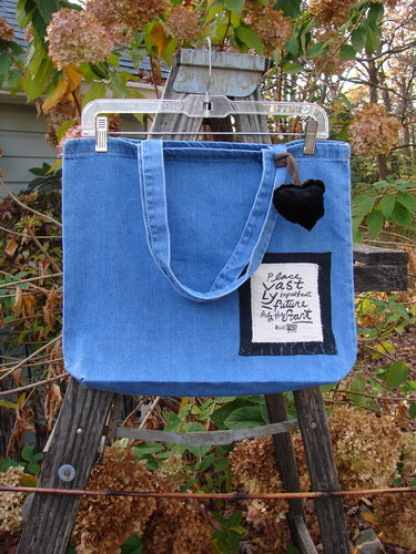 1996 PMU Patched Tote Bag Beetle Washed Denim One Size on a wooden ladder, featuring tote-length shoulder straps, a generous top opening, gusset bottom, and colorful heart and beetle patches.