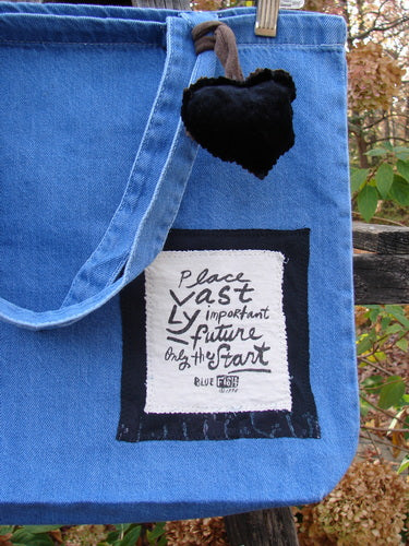 1996 PMU Patched Tote Bag Beetle Washed Denim One Size, showcasing a black heart and signature patch. Features include tote-length straps and a gusset bottom, aligned with Bluefishfinder.com's vintage, sustainable ethos.