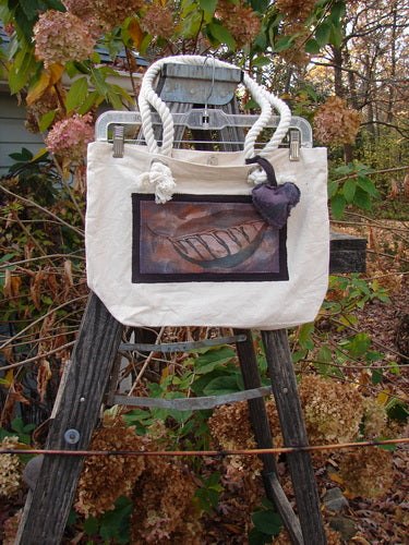 1998 PMU Patched Canvas Rope Pocket Tote Bag Ash Leaf Natural One Size displayed on a ladder, showcasing its cotton rope straps, generous top opening, and signature Blue Fish Patch with a puffy heart design.