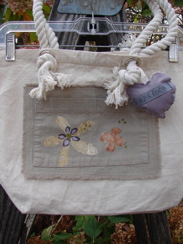 2000 PMU Patched Canvas Rope Pocket Tote Bag Daisy Natural One Size featuring a heart-shaped pillow, floral designs, and Blue Fish patches, highlighting vintage-inspired creativity and sustainable design.