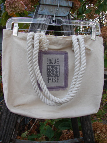 The 2000 PMU Patched Canvas Rope Pocket Tote Bag Daisy Natural One Size features a cotton rope shoulder strap, front and interior pocket patches, and a Blue Fish label, celebrating creative vintage design.