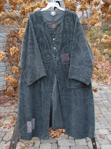 A long black coat with a damask swirl pattern, colorful patches, and vintage buttons. Size 2. Perfect condition.