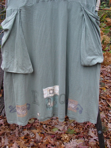 1994 PMU Patched Cross Smock Chair Garden Seaweed Size 2 hung outdoors, showcasing its oversized stitched side pockets, deep V neckline, and signature Blue Fish upper back stamp, emphasizing its unique A-line shape.