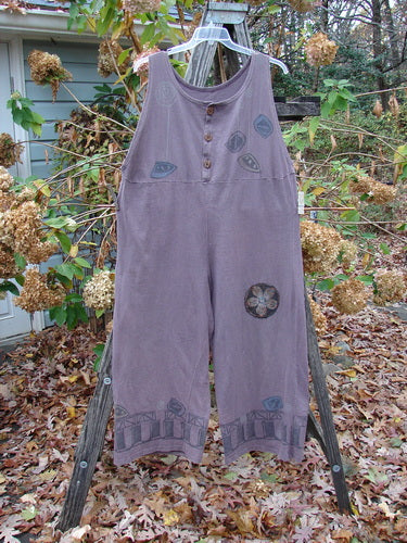 1993 PMU Patched Wide Pant Overall Jumper Travel Dusty Plum Size 1 displayed on a wooden rack, featuring wide belled legs, front buttons, and added flower patches, exemplifying vintage Blue Fish style.