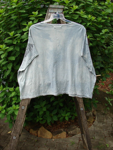 Barclay Cricket Cap Sleeve Tee Pine Forest Blue Dawn OSFA displayed on a wooden ladder, showcasing its cool cap sleeves, seamless shoulder design, and rounded hemline, emphasizing the tee's unique boxy shape.