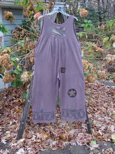 1993 PMU Patched Wide Pant Overall Jumper Travel Dusty Plum Size 1 displayed on a wooden rack, featuring wide belled legs and a flower patch on the back.