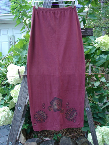 1996 Cotton Lycra Column Skirt River Rock Cayenne Size 1 displayed on a wooden ladder, showcasing its full flattened elastic waistline, tapering shape, and pegged hemline.