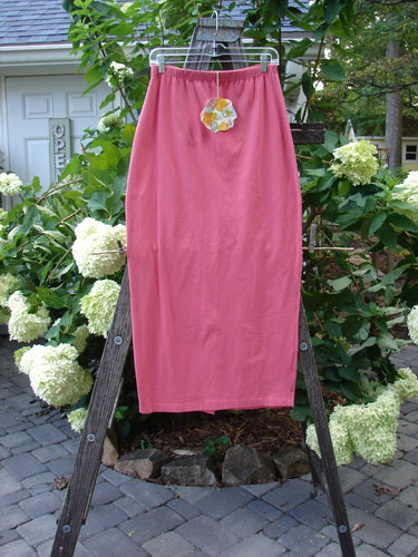 1996 NWT Cotton Lycra Column Skirt Unpainted Oriole Size 2 displayed on a wooden ladder, showcasing its full flattened elastic waistline and slimming pegged hemline with a back kick vent.