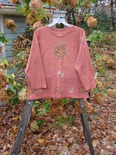 1991 Long Sleeved Tee Sun Guy Brick OSFA displayed on a wooden stand, showcasing a sun drawing. The shirt captures the unique, vintage style of BlueFishFinder's creative clothing line.