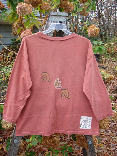 The 1991 Long Sleeved Tee Sun Guy Brick OSFA displayed on a hanger showcases vintage Blue Fish Clothing's creative design, featuring a unique pattern on soft fabric, aligning with Bluefishfinder.com's distinctive style.