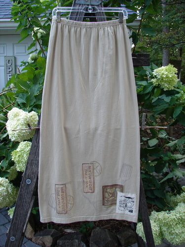 1998 Straight Skirt Airmail Quill Size 0 displayed on a wooden ladder, showcasing its full elastic waistband and airmail travel theme around the hem, made from mid-weight organic cotton.