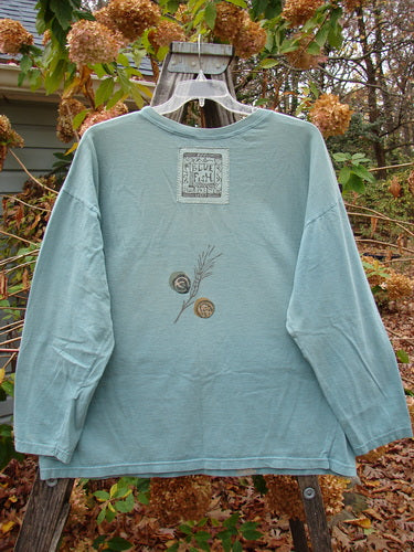 The image shows the 1993 Long Sleeved Tee Medallian Field Ocean OSFA, displayed on a swinger. This vintage Blue Fish Clothing piece features a relaxed fit, highlighting its timeless appeal and creative expression.