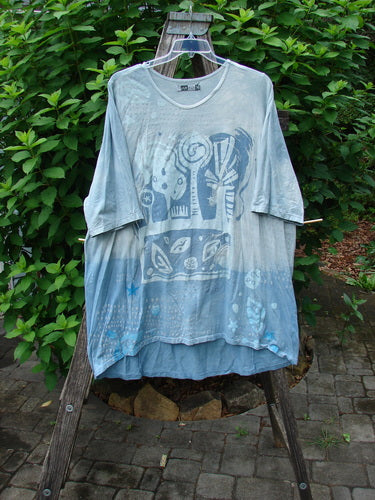 Barclay Tournesol Tunic Flower Power Mottled Day Sky OSFA displayed on a swinger, showcasing its longer tunic length, drop shoulders, loose sleeves, and varying hemline in a natural outdoor setting.