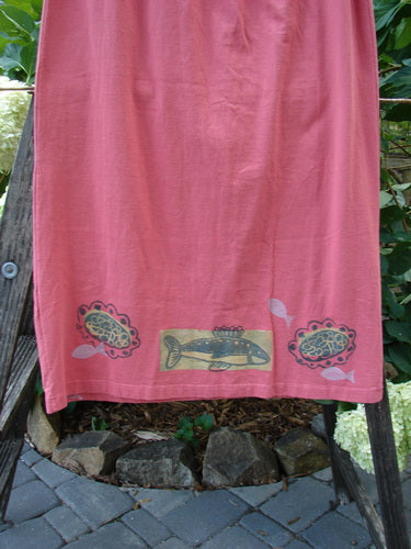 1996 Straight Skirt River Fish Oriole Size 0, displayed hanging outdoors, showcasing its full elastic waistband and intricate fish pattern. The skirt's organic cotton fabric and slight A-line shape are visible.