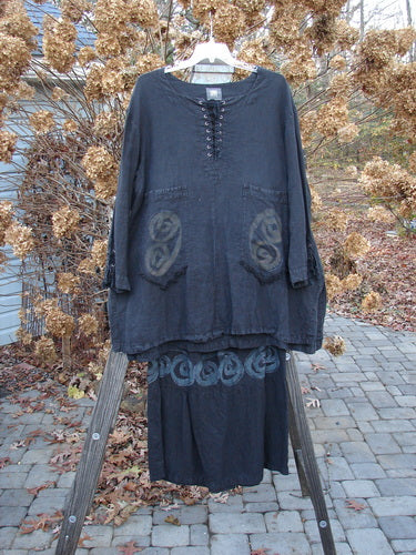 2000 Pages Market Duo Celtic Black Size 2: A black shirt on a rack, featuring a laced front and sleeve, side vents, and a varying hemline.