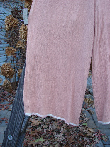 1998 Gauze Shell Layering Duo Tiny Floral Blush Size 2: A person's leg wearing pink pants with a rope and wooden pole.