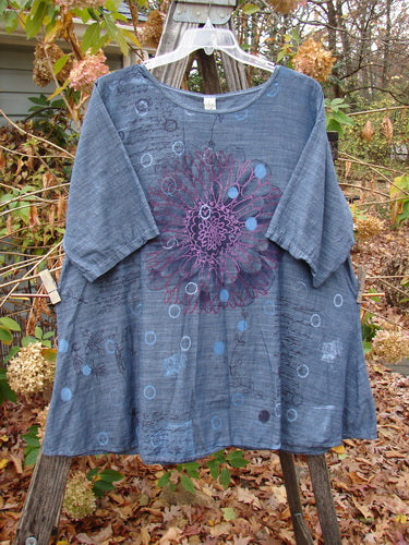 Barclay Woven Short Sleeved Pullover Tunic Mum Cross Dye Navy Size 1, featuring a purple flower design on a blue background, displayed on a wooden rack, highlighting its lightweight cotton fabric and unique pattern.