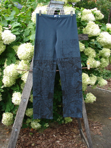 Barclay Cotton Lycra Straight Pant City Plan Lux Silhouette Size 0 in dark navy, with a straight-leg cut and subtle city-map line print. The cotton-lycra fabric hangs from a wooden ladder outdoors, framed by white hydrangeas and green foliage.