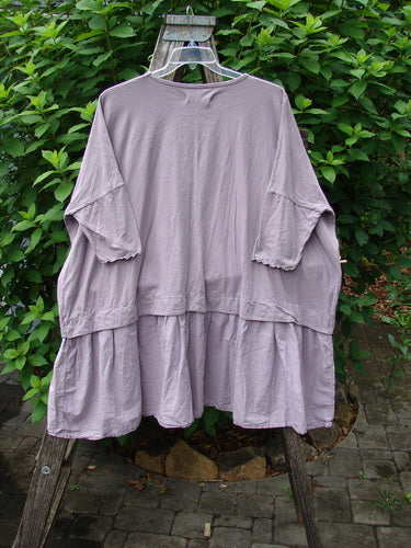 Barclay NWT Batiste Banded Flounce Esperanza Tunic in Sea Fog displayed on a clothes rack, featuring dolman sleeves, a rounded neckline, and a boxy shape with a floral paint theme.