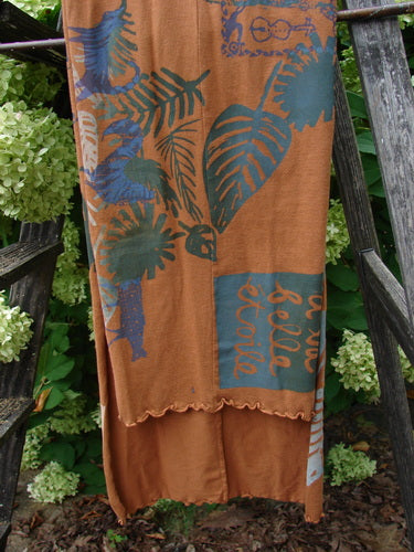 Barclay Curly Edge Center Seam Scarf Wrap in fall forest friend rust, with a soft rust base, teal-blue botanical prints, and a curly scalloped edge. The long wrap hangs in layered folds, showing a center seam and a smooth, lightweight fabric.