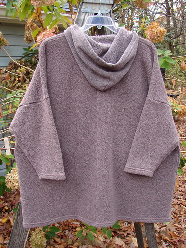 Barclay Fleece Hooded Square Pocket Pullover, featuring a soft, patterned fabric and cozy hood, hanging on a clothesline. Crafted from heavy weight organic cotton with recycled poly, emphasizing comfort and individuality.