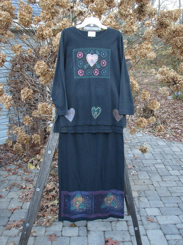 1999 Vented Straight Duo Heart Black Size 1: Long black dress with hearts on a wooden ladder. Perfect condition, made from organic cotton. Features include rolled neckline, vented sides, drop shoulders, and colorful mosaic heart theme paint. Straight skirt with elastic waistline and colorful mosaic hearts. Measurements: Bust 50, Waist 50, Hips 50, Front Length 29, Back Length 32. Vintage Blue Fish Clothing from the Winter Collection of 1999.