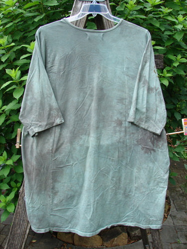 Barclay Tournesol Tunic Spotted Cat Mottled Grass Field OSFA displayed on a hanger, showcasing its drop shoulders, loose three-quarter sleeves, and varying hemline with a side garden and spotted cat motif.