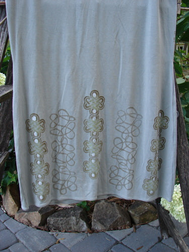 2000 Rayon Lycra Narrow Skirt Celtic Celebration Ash Size 2, featuring a white towel with gold designs, displayed on a wooden railing.