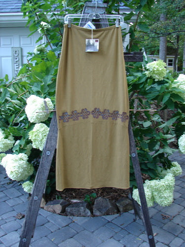 2000 NWT Rayon Lycra Narrow Skirt Celtic Celebration Bone Size 2 displayed on a wooden rack, featuring a full thinner flattened elastic waistband and horizontal sectional panels.