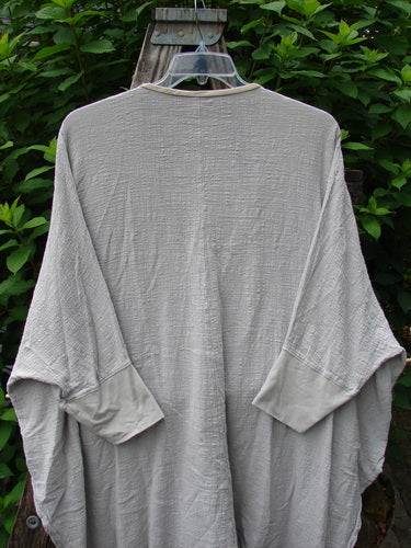 Barclay Gauze Open Front Cardigan Unpainted Natural Size 2 displayed on a hanger, featuring generous dolman sleeves, open front, tall vented sides, and contrasting lower cuffs, highlighting its airy design.