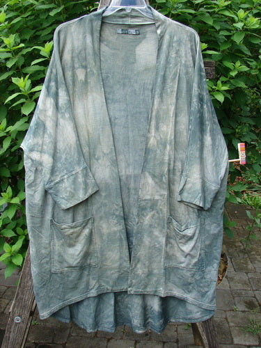 Barclay Bamboo Dolman Day Jacket, showcased hanging on a wooden pole, features dolman sleeves, open front, drop pockets, cuffed sleeves, and a vintage floral rear design, epitomizing Blue Fish Clothing's creative expression.