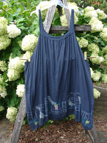 Barclay Batiste Banded Collar Slip Dress Birdy Border in black, size 2, with slim shoulder straps and a softly gathered bodice that falls into a loose, airy silhouette. The dark fabric shows a subtle birdy border pattern near the hem, hanging against a rustic wooden ladder amid pale hydrangea blooms and green foliage.
