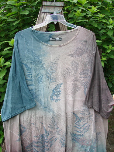 Barclay Art Tee Fern Garden Mottled Pure Dawn OSFA displayed outdoors on a swinger, showcasing its tunic length, drop shoulders, loose three-quarter sleeves, rounded neckline, and varying hemline.