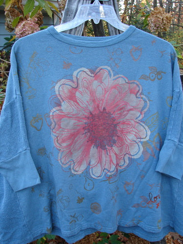 Barclay Hemp Cotton Banded Sleeve Dolman Top Mum Blue Dusk OSFA features a blue shirt adorned with a floral design, showcasing a close-up of a flower, embodying BlueFishFinder's vintage, expressive style.