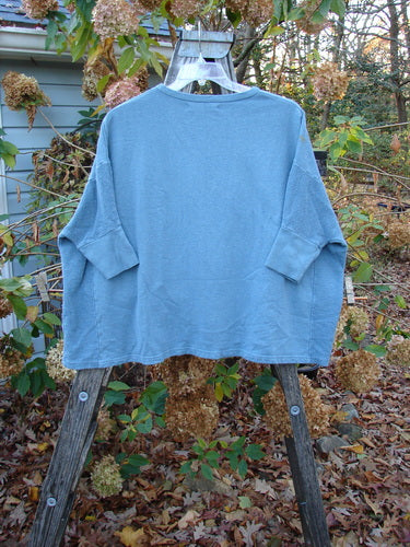 Barclay Hemp Cotton Banded Sleeve Dolman Top Mum Blue Dusk OSFA displayed on a wooden rack outdoors, highlighting its unique design and fabric texture, embodying Bluefishfinder.com's vintage, expressive style.