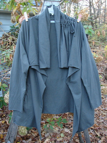 Barclay Cotton Lycra Gather Collar Open Front Jacket Unpainted Forest Size 2 hangs on a rack, showcasing its medium weight and pocketed design, epitomizing Bluefishfinder.com's vintage-inspired outerwear collection.