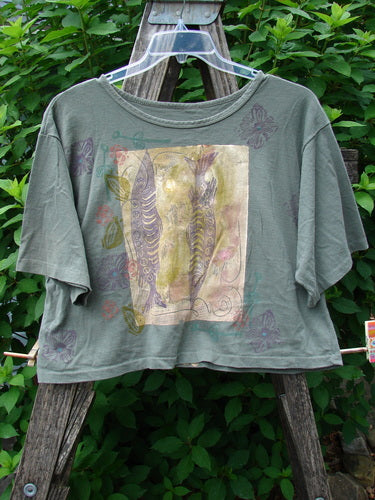1991 Short Sleeved Crop Tee Fish Flower Olive Drab OSFA displayed on a swinger, showcasing its vintage rolled neckline and unique double fish and flower design, highlighting a slightly faded area at the rear center.
