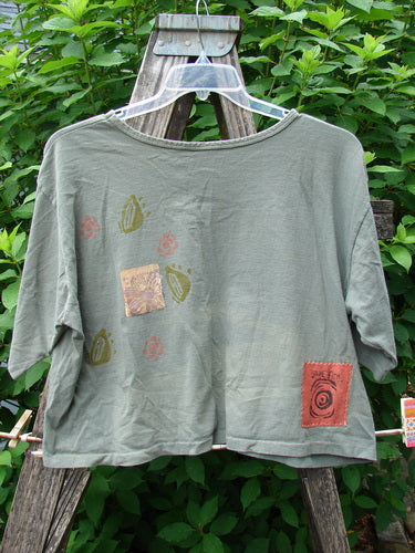 1991 Short Sleeved Crop Tee Fish Flower Olive Drab OSFA features vintage double fish and continuous flower paint on an olive drab crop top, showcasing a rolled neckline and slight rear center fade.